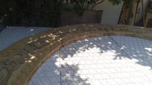 מקרוב: קשת העץ המגולפת מונחת על גבי הסבכה הלבנה בצל עצים