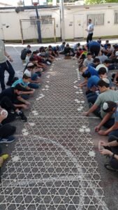 נערים משני צדי רצועת סבכה ארוכה בחצר בית הספר מחברים את חלקיה