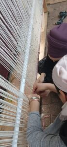 קשירת חוטי השתי בתחתית הנול האנכי הגבוה